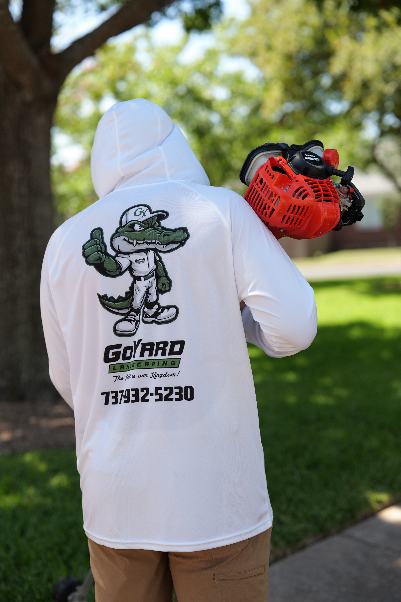 Go Yard Landscaping crew member in branded gear carrying an edger